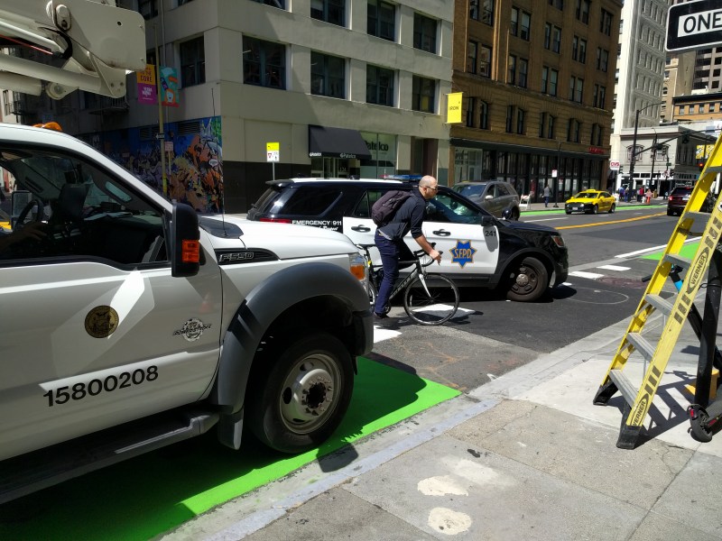 The city truck parked on the bike lane and an SFPD cruiser making a dangerous, un-signaled turn on a typical day in 2019 of city employees driving recklessly. Photo: Streetsblog/Rudick