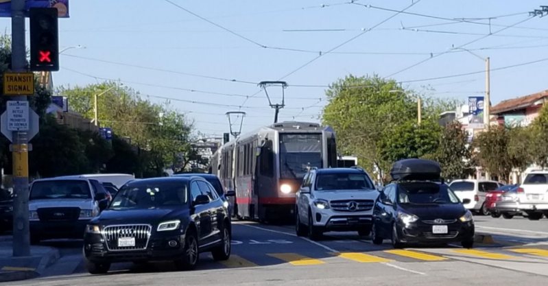 A train full of 100 people or more waiting behind private vehicles on West Portal Avenue. Photo: SFMTA