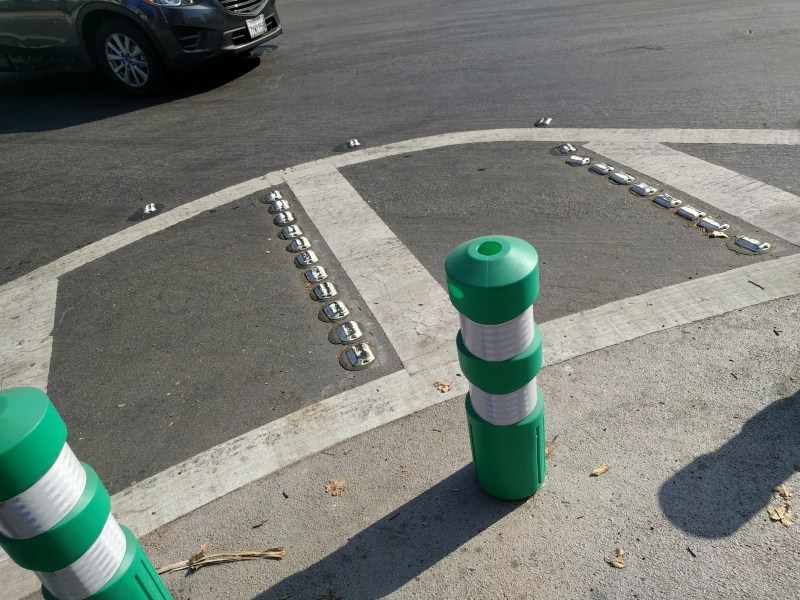 A corner on a protected intersection in San Jose, with two radii. The outer one, made of reflective bumps, warns drivers that they're taking the turn too close.
