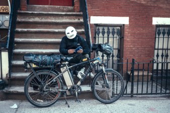 A delivery worker with his e-bike and multiple batteries. These essential workers toil under onerous conditions in order to deliver a hungry city its grub. File photo