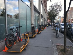 Cargo bikes and trailers are parked on the sidewalk outside the Whole Foods Market on Houston Street in New York City in this 2019 file photograph. Courtesy of StreetsblogNYC.