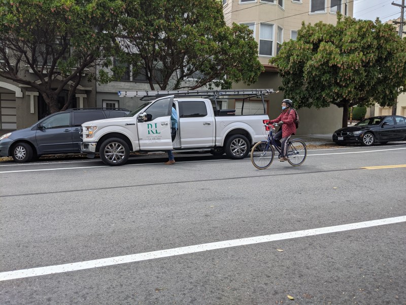 A cyclist navigates around a truck parked on the new bike lane. Photos: Streetsblog/Rudick