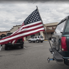 Image description: an American flag attached to the bumper of a large SUV. Source: Robert Couse-Baker, PxHere, CC