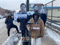 Alfred White, a temp worker and volunteer with Warehouse Workers Together, speaks at the event. Behind him attendees hold Rosa Parks cutouts. Photo: Cameron Bolton