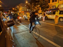 A cyclist goes around a double-parked car during last night's protest, assisted by the demonstrators. Photo: Streetsblog/Rudick