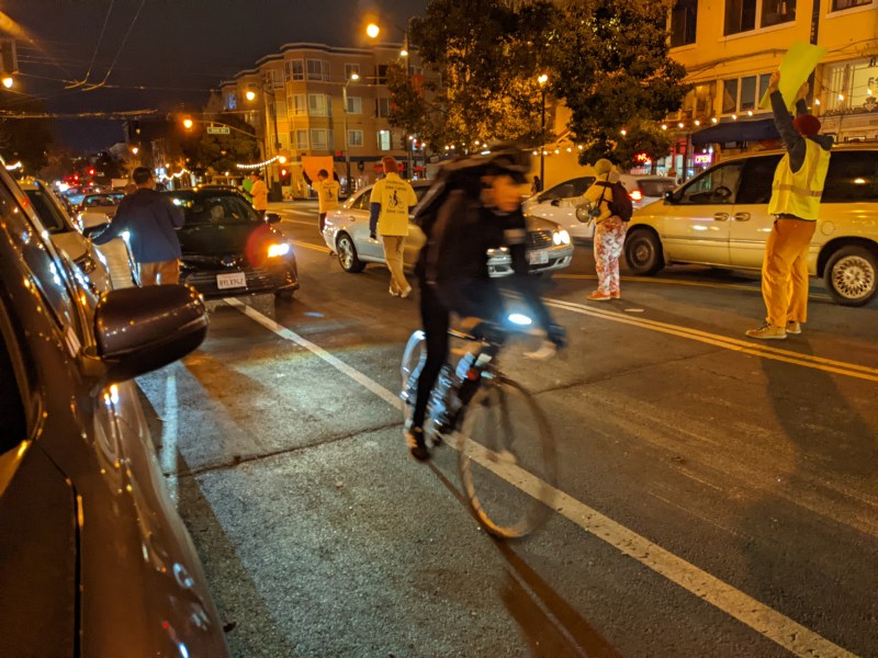 A cyclist goes around a double-parked car during last night's protest, assisted by the demonstrators. Photo: Streetsblog/Rudick