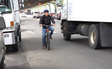 A delivery worker on an e-bike maneuvers around a truck. Photo: file